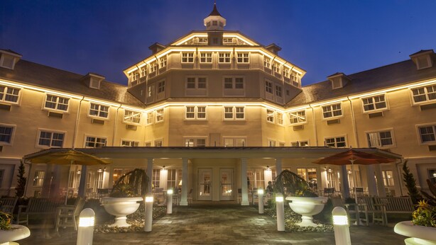 Un hotel grande de varios pisos con un patio central, varios balcones y una torre destacada.
