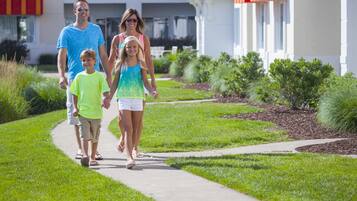 Une famille se promène sur un trottoir devant un immeuble surmonté d’un auvent rouge.