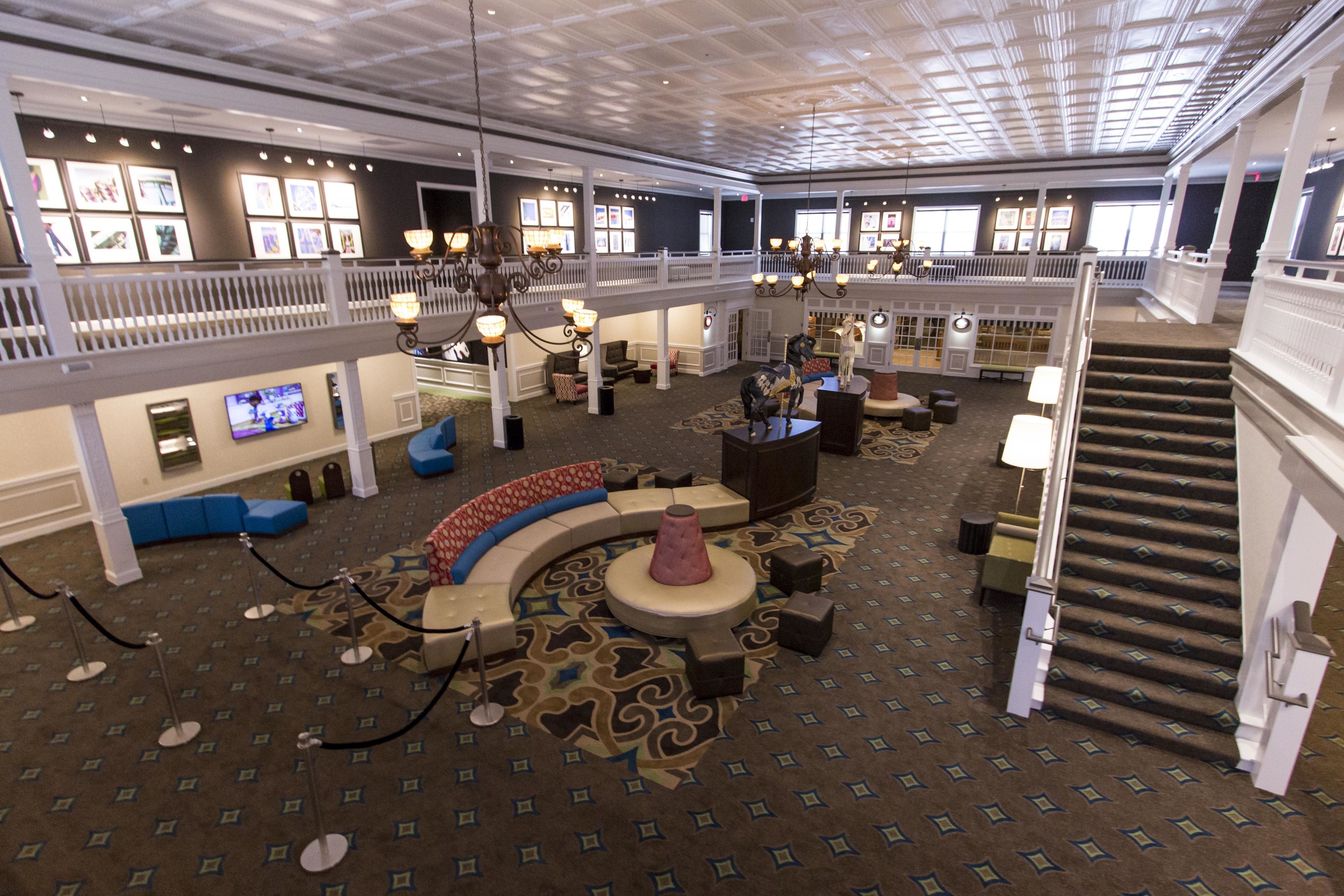 A spacious lobby with a high ceiling, multiple seating areas, and a staircase.