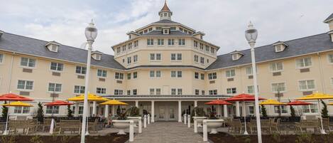 A large, multi-story hotel with a central entrance, outdoor seating with umbrellas, and a symmetrical facade.