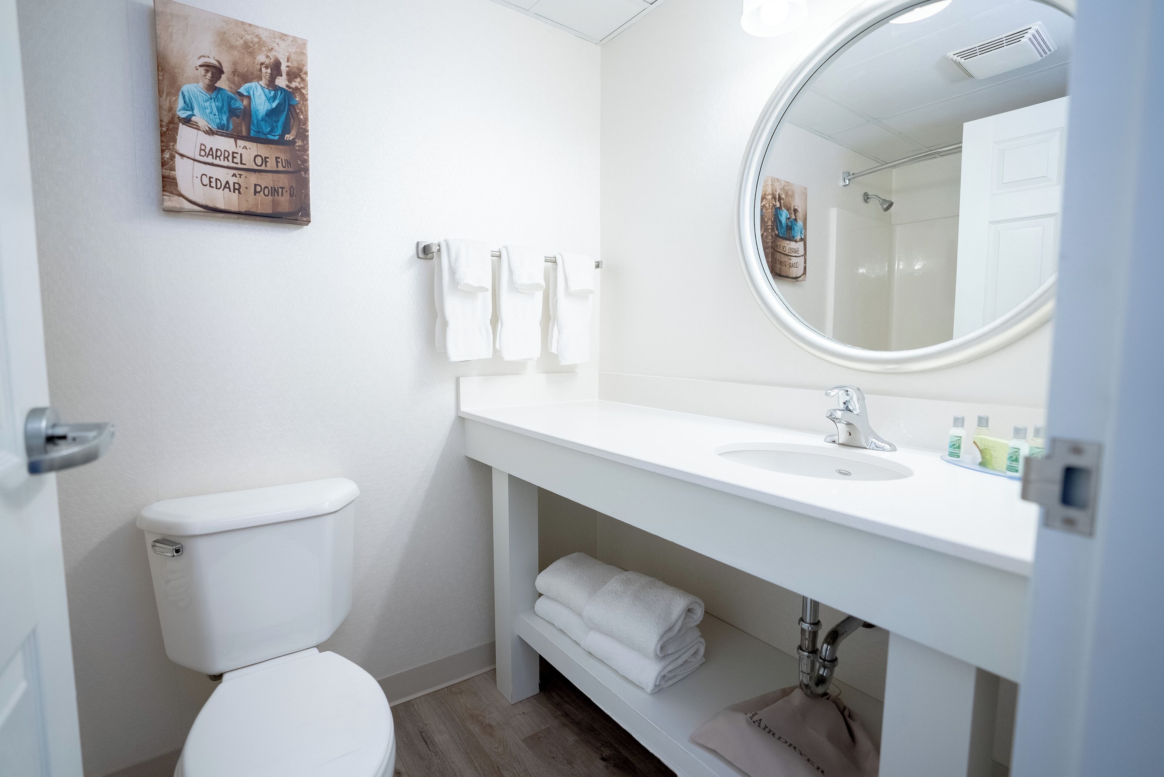 Une salle de bain avec des toilettes blanches, un lavabo, un miroir et un porte-serviettes.