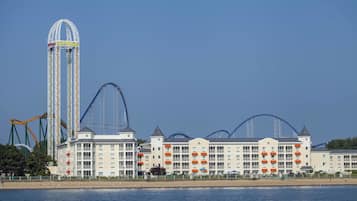 A hotel with multiple floors, a prominent tower, and adjacent amusement park rides.