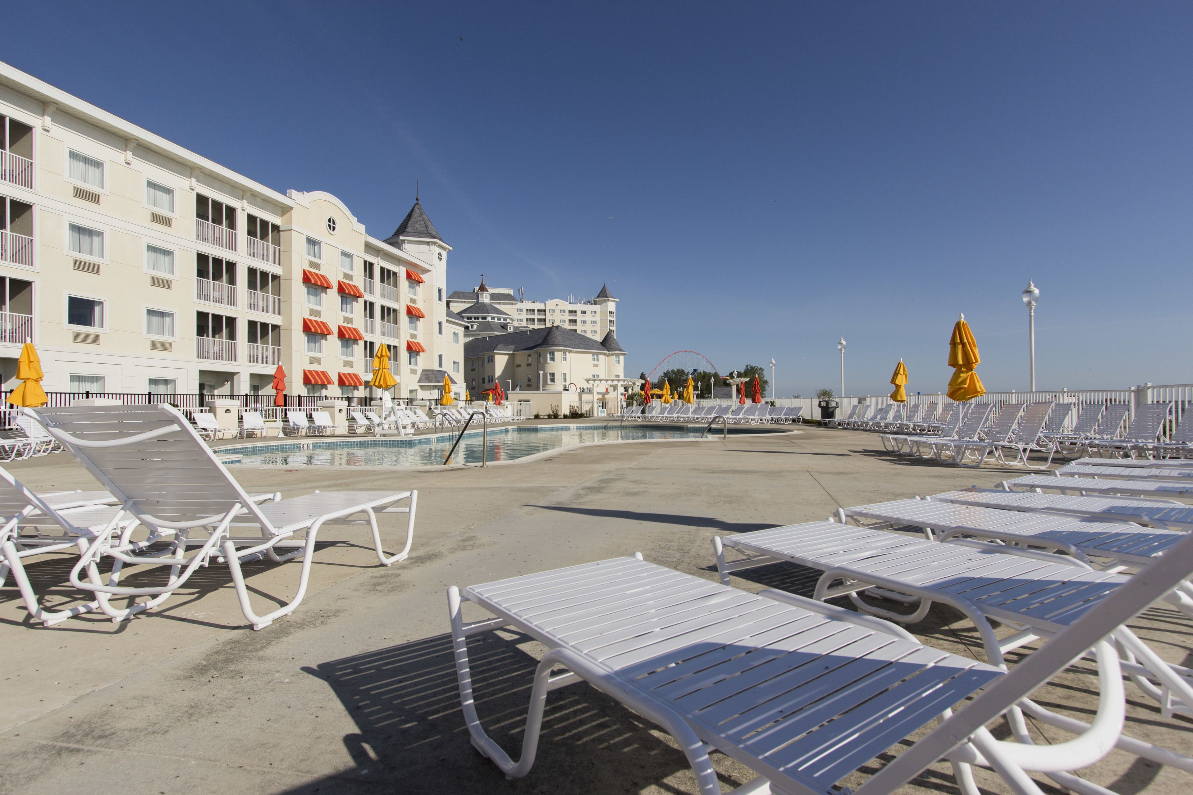 Un hotel con piscina, sillones de descanso blancos y sombrillas amarillas.