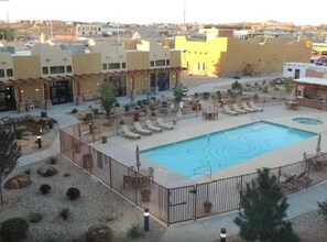 Un área de piscina en la azotea con sillones de descanso y una piscina.