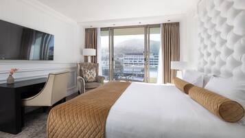 A hotel room with a large bed, a desk, a chair, and a television.