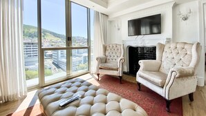 A spacious living room with a large window, a fireplace, and two armchairs.