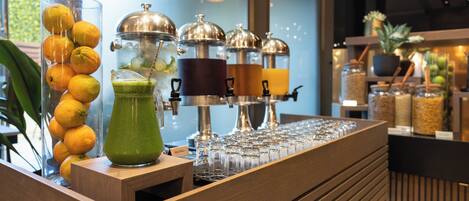 A bar area with a wooden counter, a glass container with lemons, a green drink, and a coffee machine.