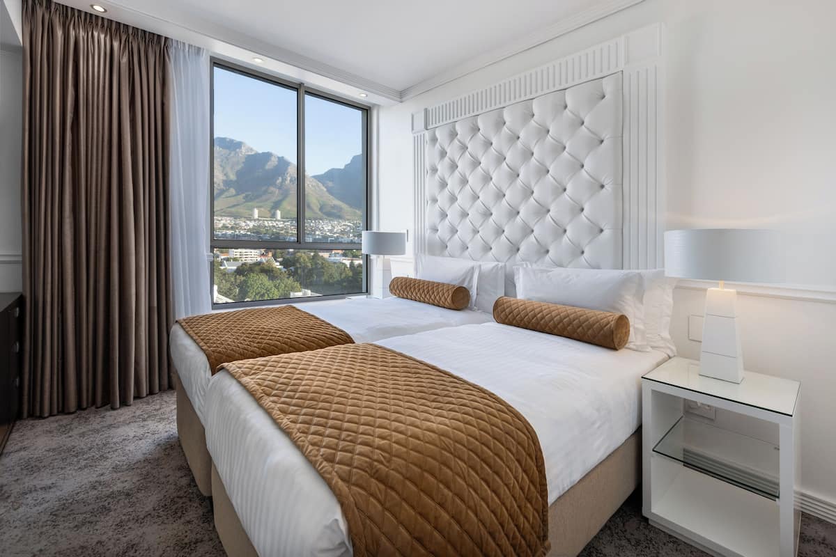 Una habitación de hotel con una cama grande, una mesita de noche y vistas a montañas.