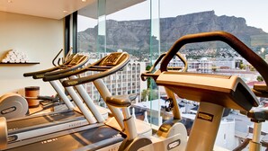 A gym with cardio equipment and a view of a cityscape and mountains.