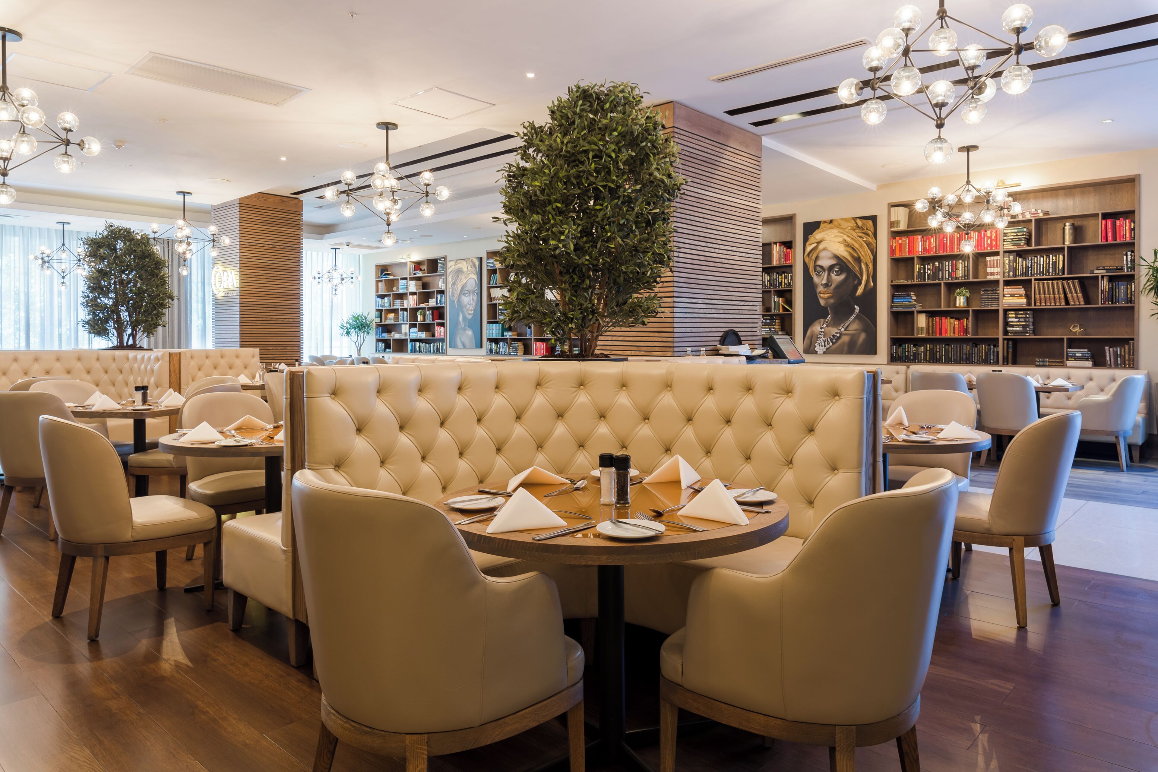 A modern restaurant with a central seating area featuring a tufted backrest and round tables.