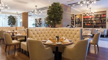 A modern restaurant with a central seating area featuring a tufted backrest and round tables.