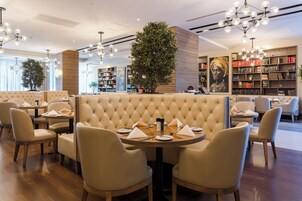 A modern restaurant with a central seating area featuring a tufted backrest and round tables.