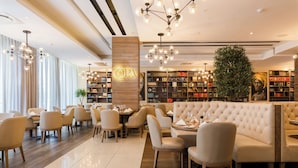 A modern hotel lobby with a central seating area, a bookshelf, and a large plant.