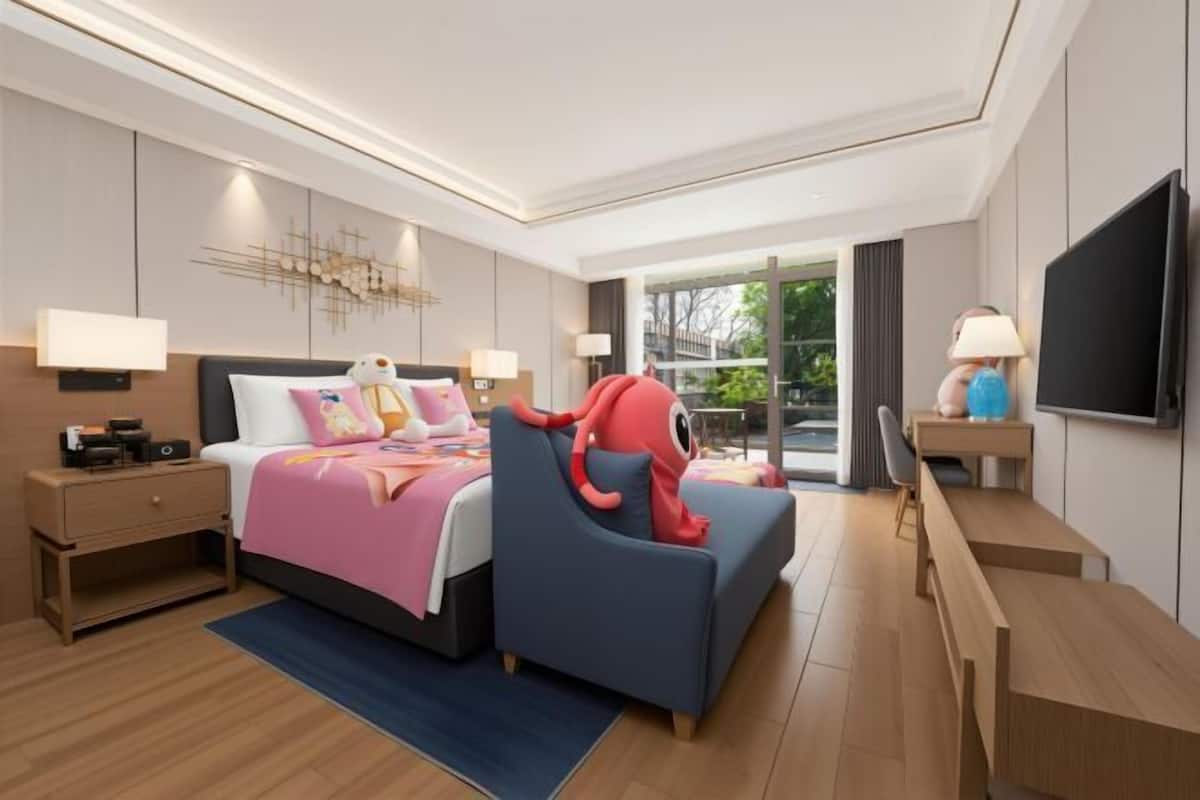 A modern hotel room with a bed, a desk, a chair, a TV, and a window with a view.