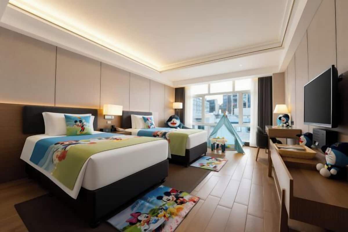 A hotel room with a large bed, two bedside tables, a TV, and a window with a city view.