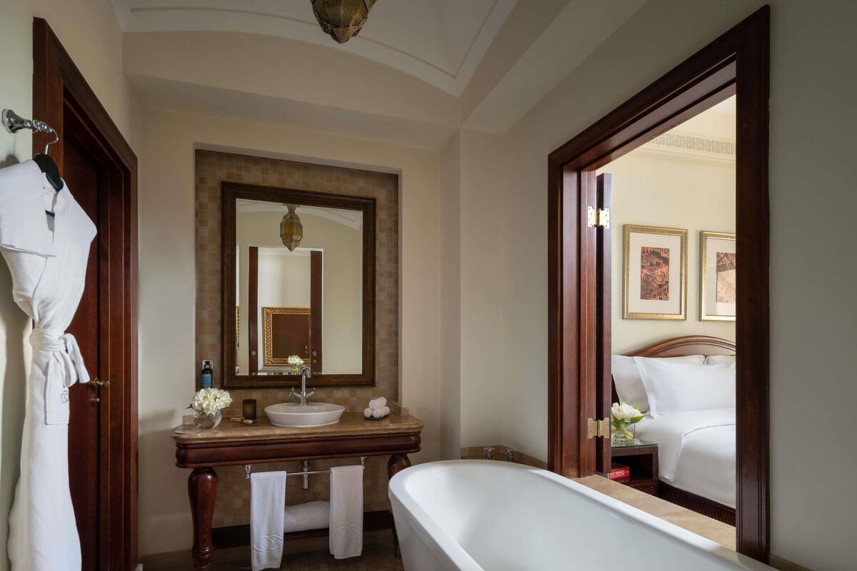 A bathroom with a large mirror, a bathtub, a sink, and a vanity.