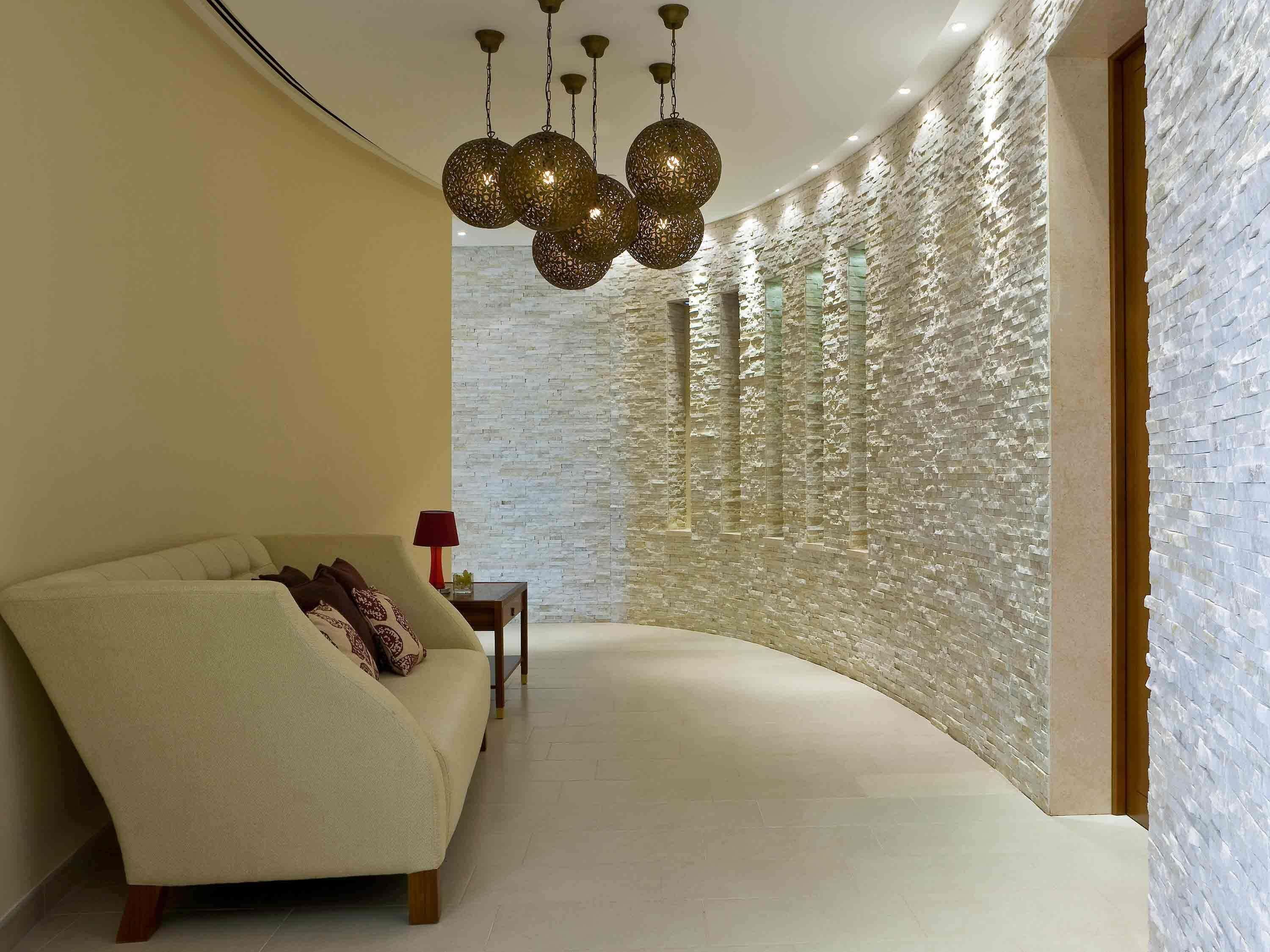 A modern interior with a curved wall, a sofa, and a hanging light fixture.