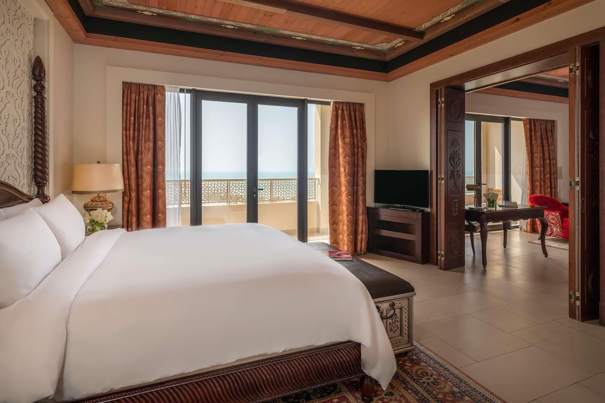 A hotel room with a large bed, a television, a desk, and a balcony with a view.
