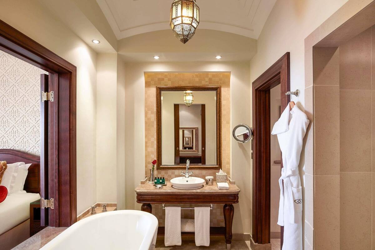 A bathroom with a bathtub, a sink, and a large mirror.