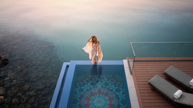 Una persona al costat d'una piscina sense fi amb una vista clara de l'aigua.