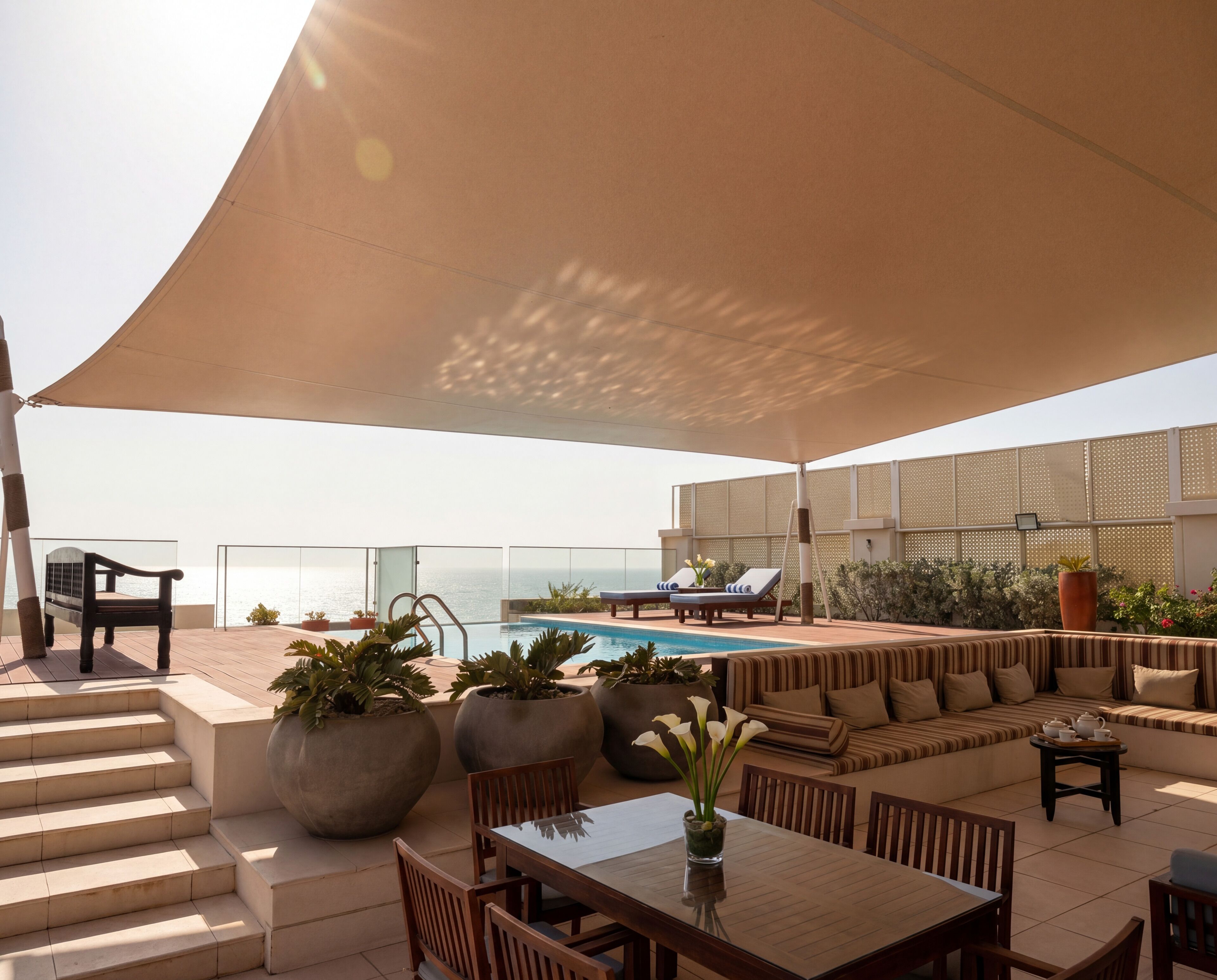 A rooftop terrace with a pool, seating area, and potted plants.
