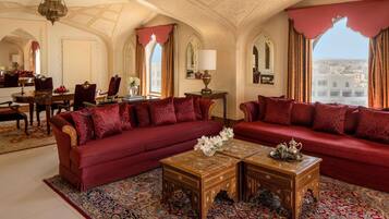 A luxurious room with a red sofa set, ornate wooden coffee table, and a patterned carpet.