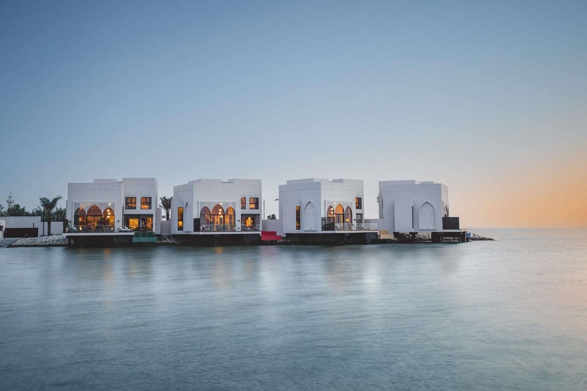 A waterfront hotel with multiple white buildings, each featuring arched windows and balconies.