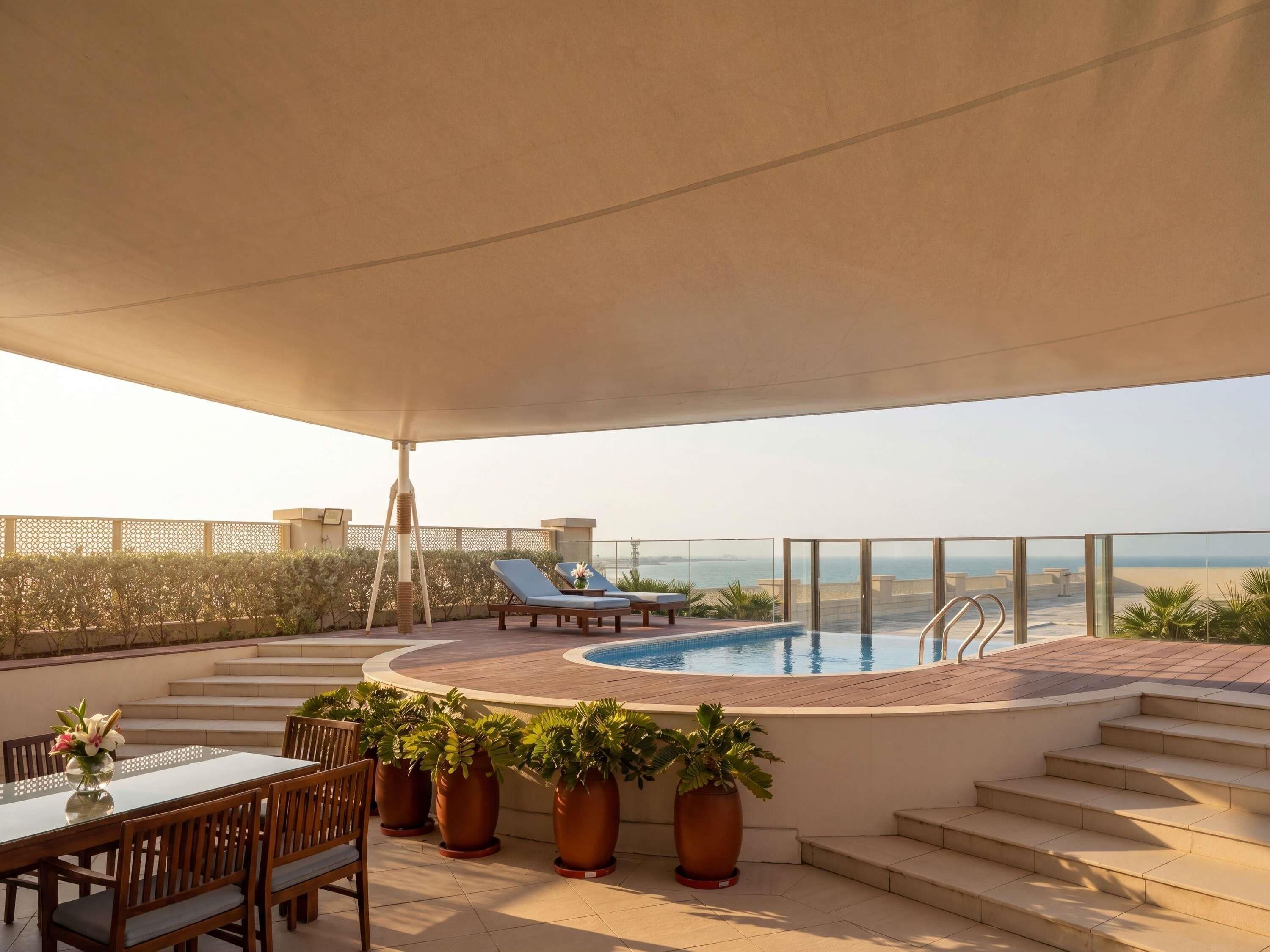 A rooftop terrace with a pool, lounge chairs, and potted plants.