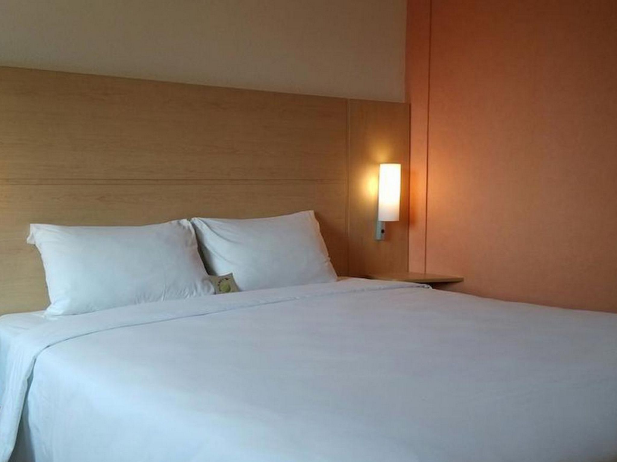En väl bäddad säng med vita lakan i ett hotellrum.
