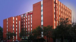 Um hotel de vários andares com fachada vermelha e janelas brancas.
