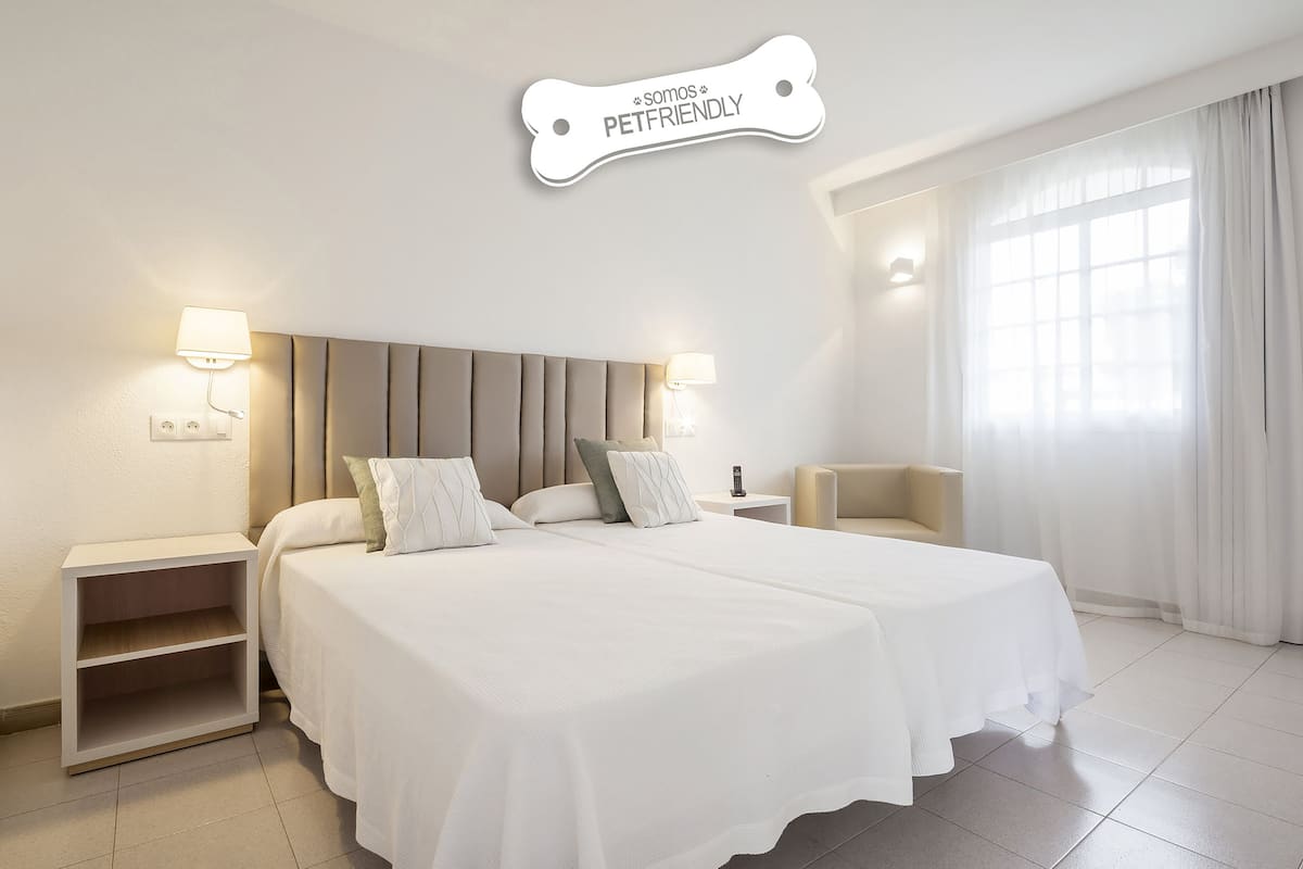 Een moderne hotelkamer met een groot bed, nachtkastjes en een raam met dunne gordijnen.