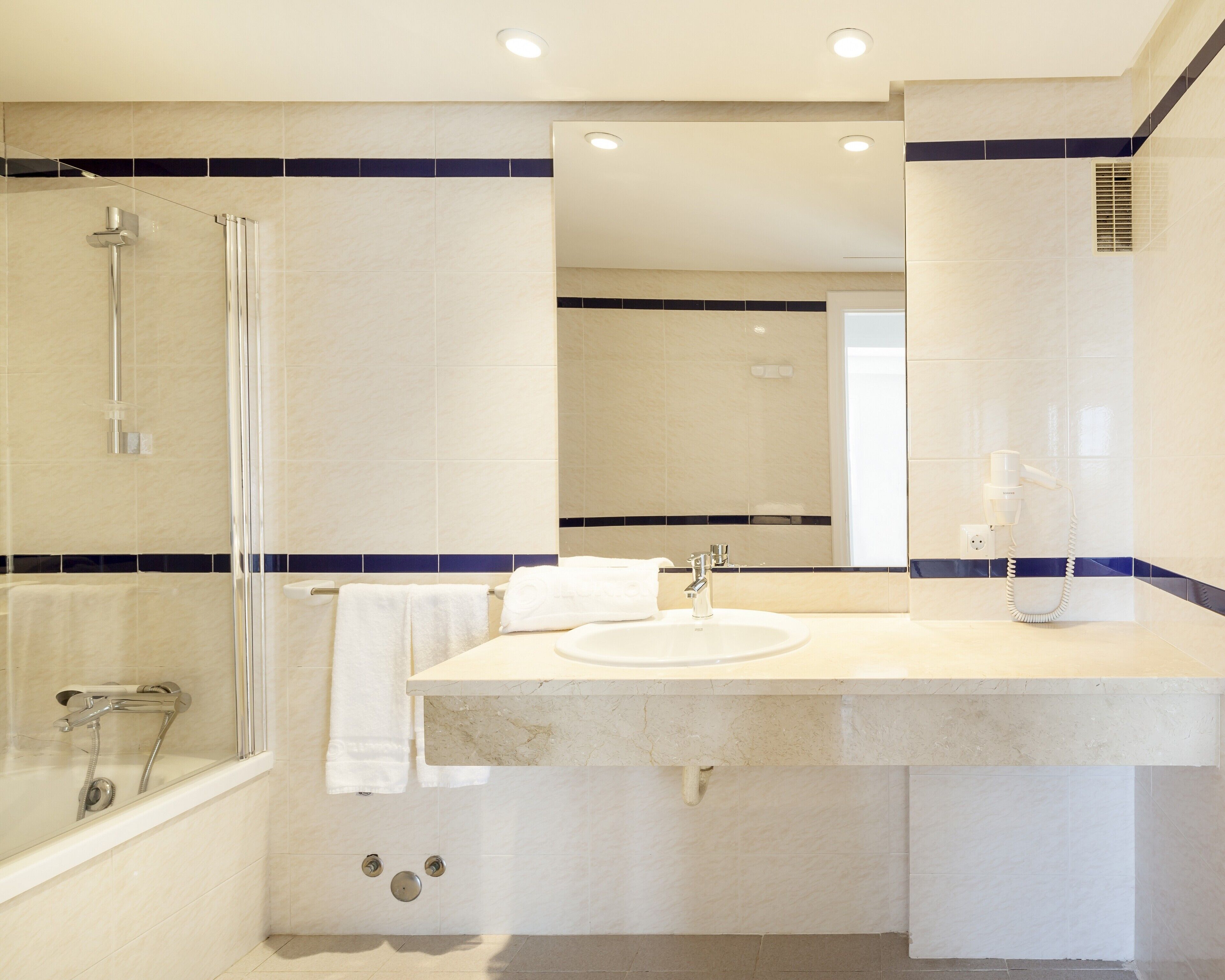 A modern bathroom with a glass-enclosed shower, a sink with a mirror, and a towel rack.