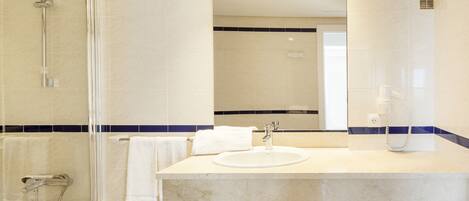 A modern bathroom with a glass-enclosed shower, a sink with a mirror, and a towel rack.