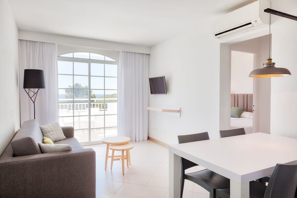 Een moderne woonkamer met een bank, een eettafel en een aan de muur bevestigde televisie.