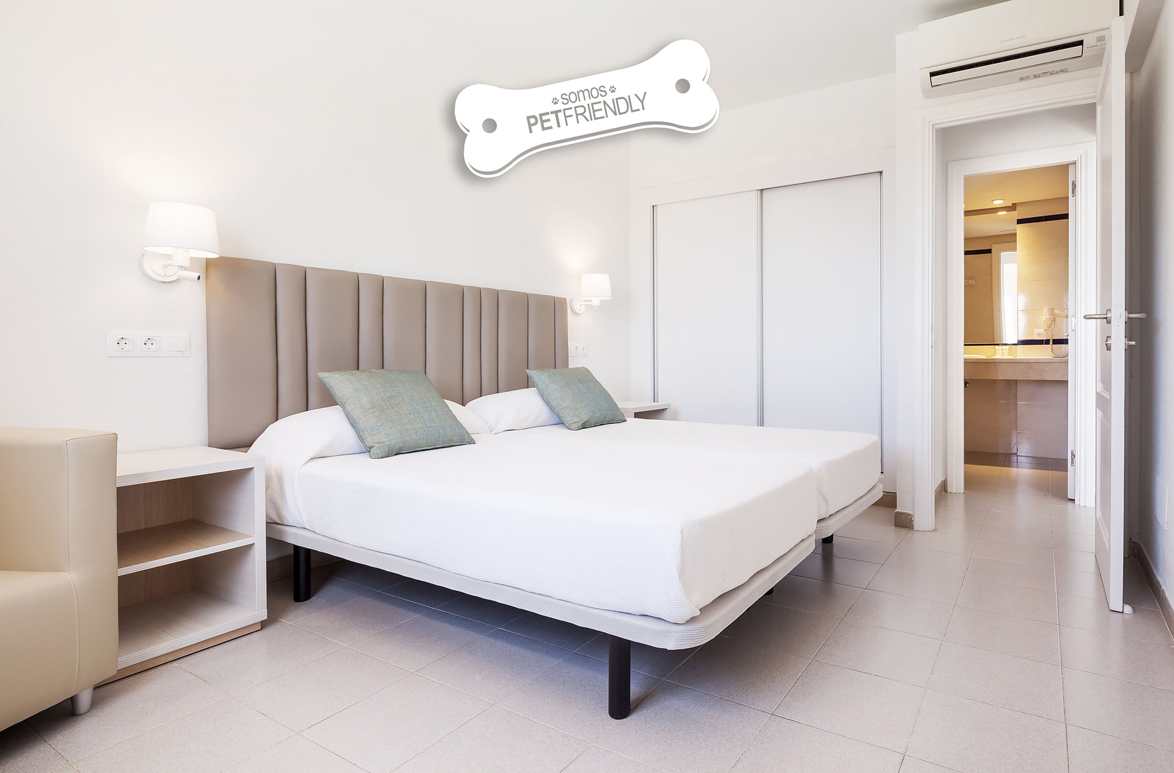 Una habitación de hotel moderna con una cama, mesitas de noche, una silla y un cartel en la pared.