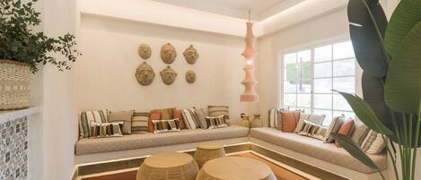 Uma sala de estar moderna com sofá, arte decorativa na parede e uma planta grande.