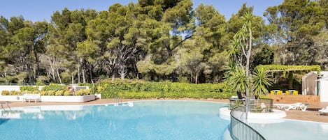 Una piscina al aire libre de temporada, sombrillas, tumbonas