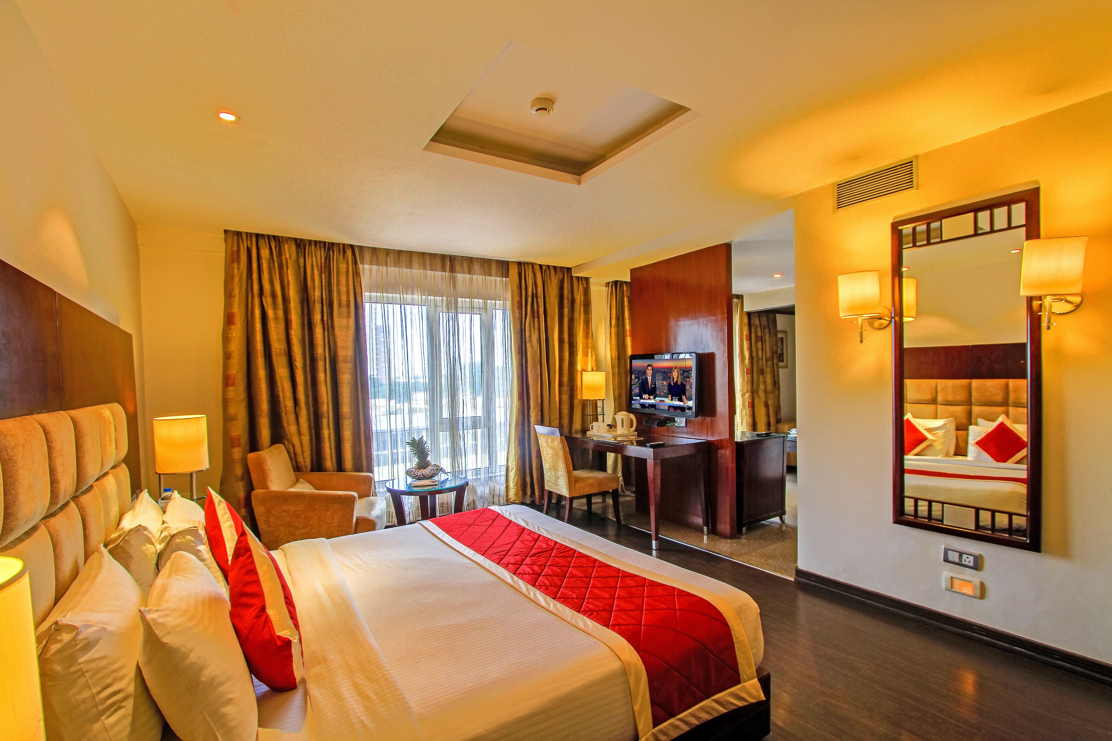 Une chambre d’hôtel avec un grand lit, un bureau, une télévision et un miroir.