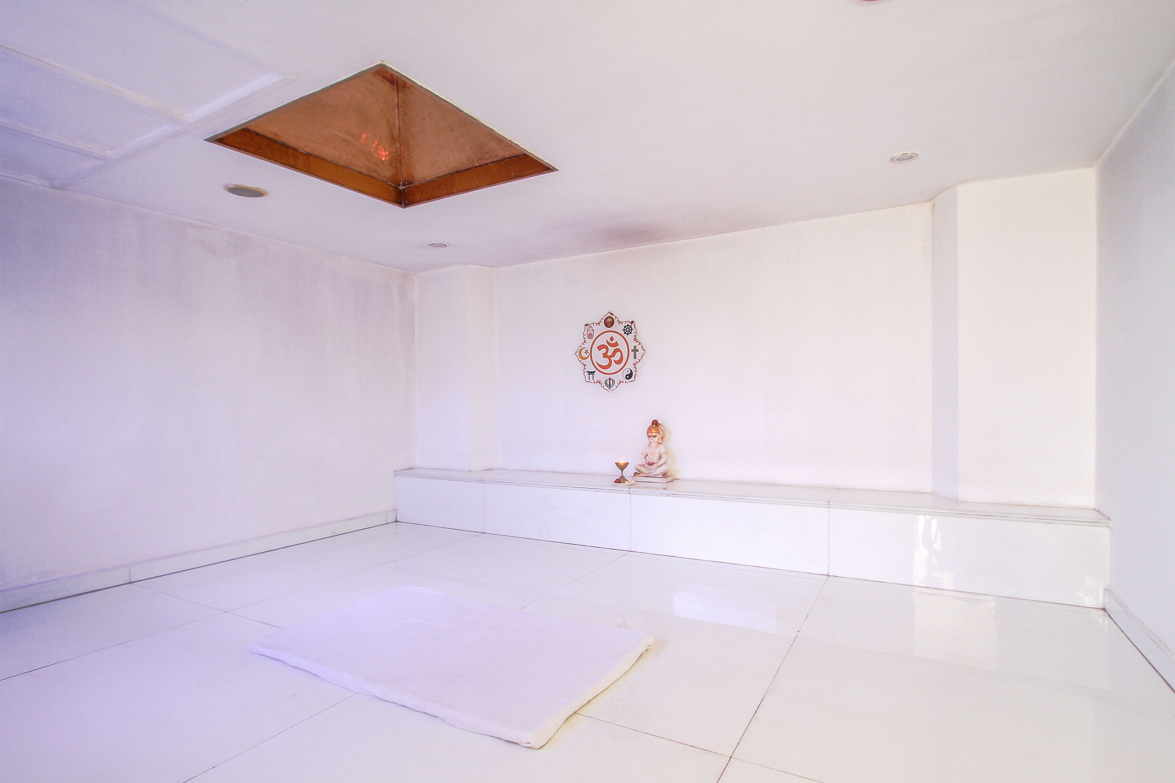 A spacious, white-walled room with a large, shiny floor, a ceiling light fixture, and a wall-mounted decorative item.