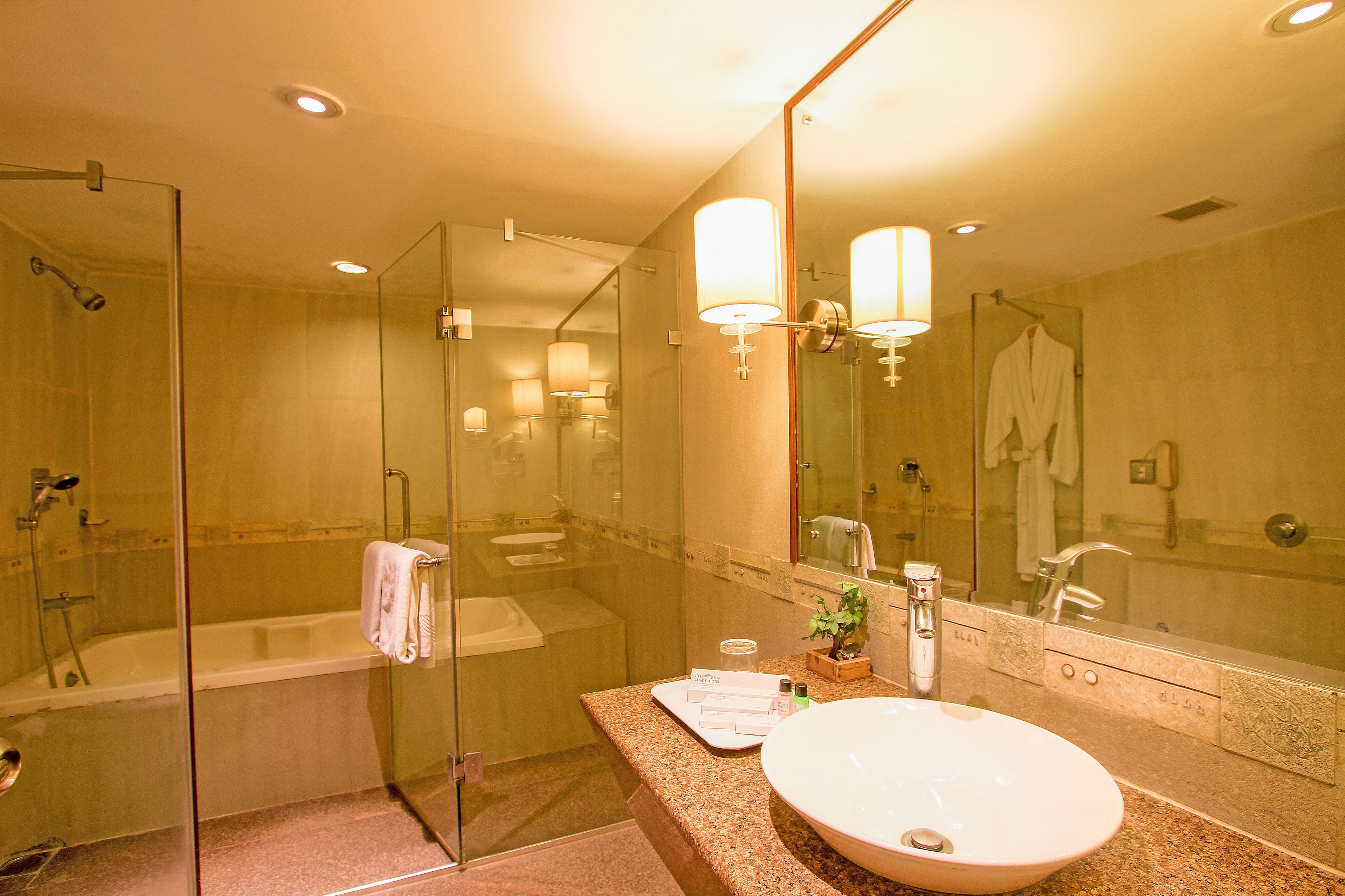 A modern bathroom with a glass-enclosed shower, a large sink, and a mirror with a light fixture.
