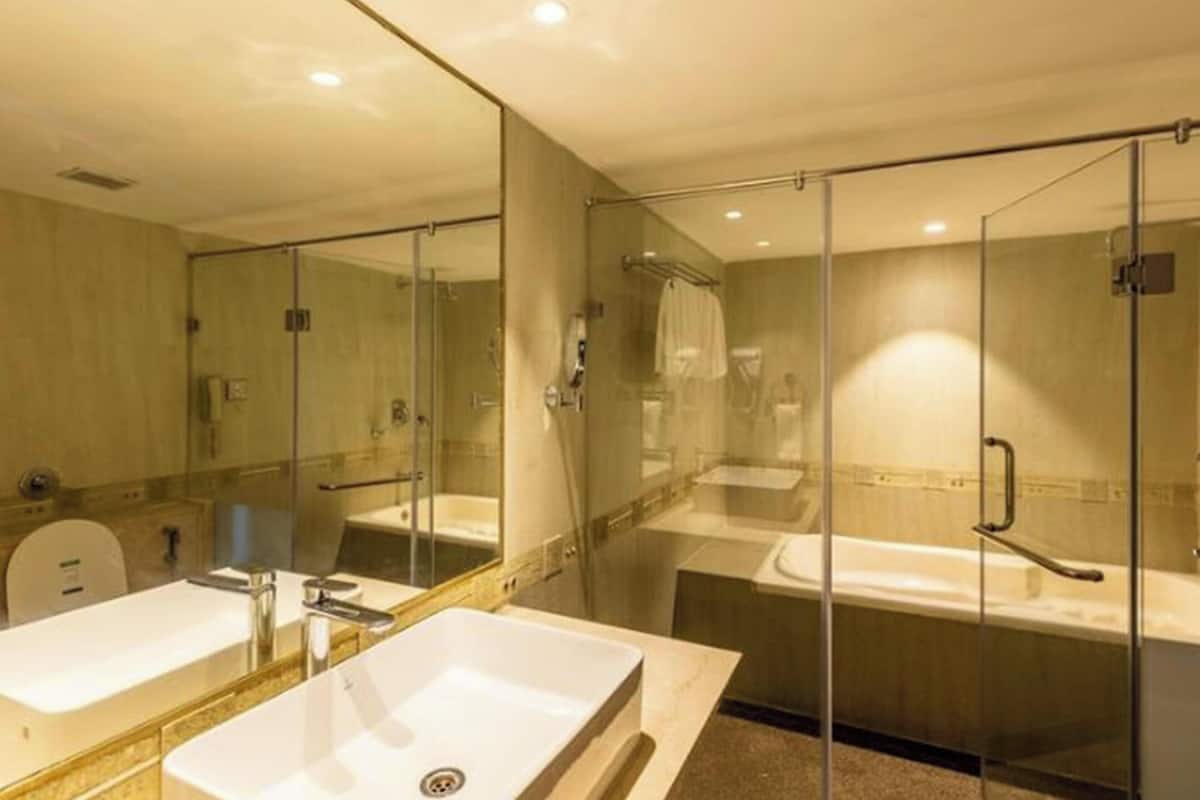 Une salle de bain moderne avec un grand miroir, deux lavabos, une baignoire et une douche séparée par une paroi en verre.