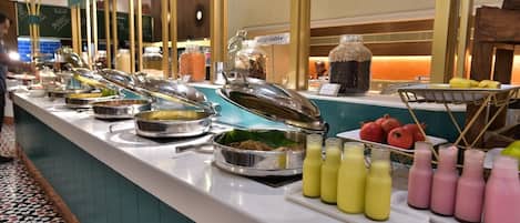 Un bufé con diferentes opciones de comida y bebidas, incluyendo una sección con menú vegetariano.