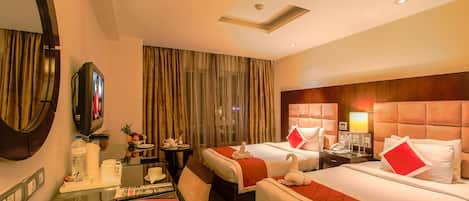 A hotel room with two beds, a desk with a chair, a TV, and a minibar.