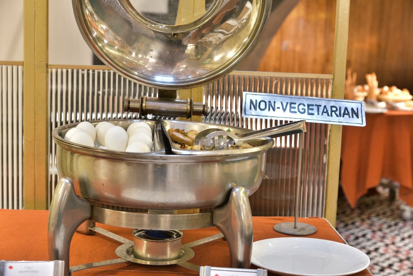 A buffet setup with a non-vegetarian sign, a pot of boiling eggs, and a ladle.
