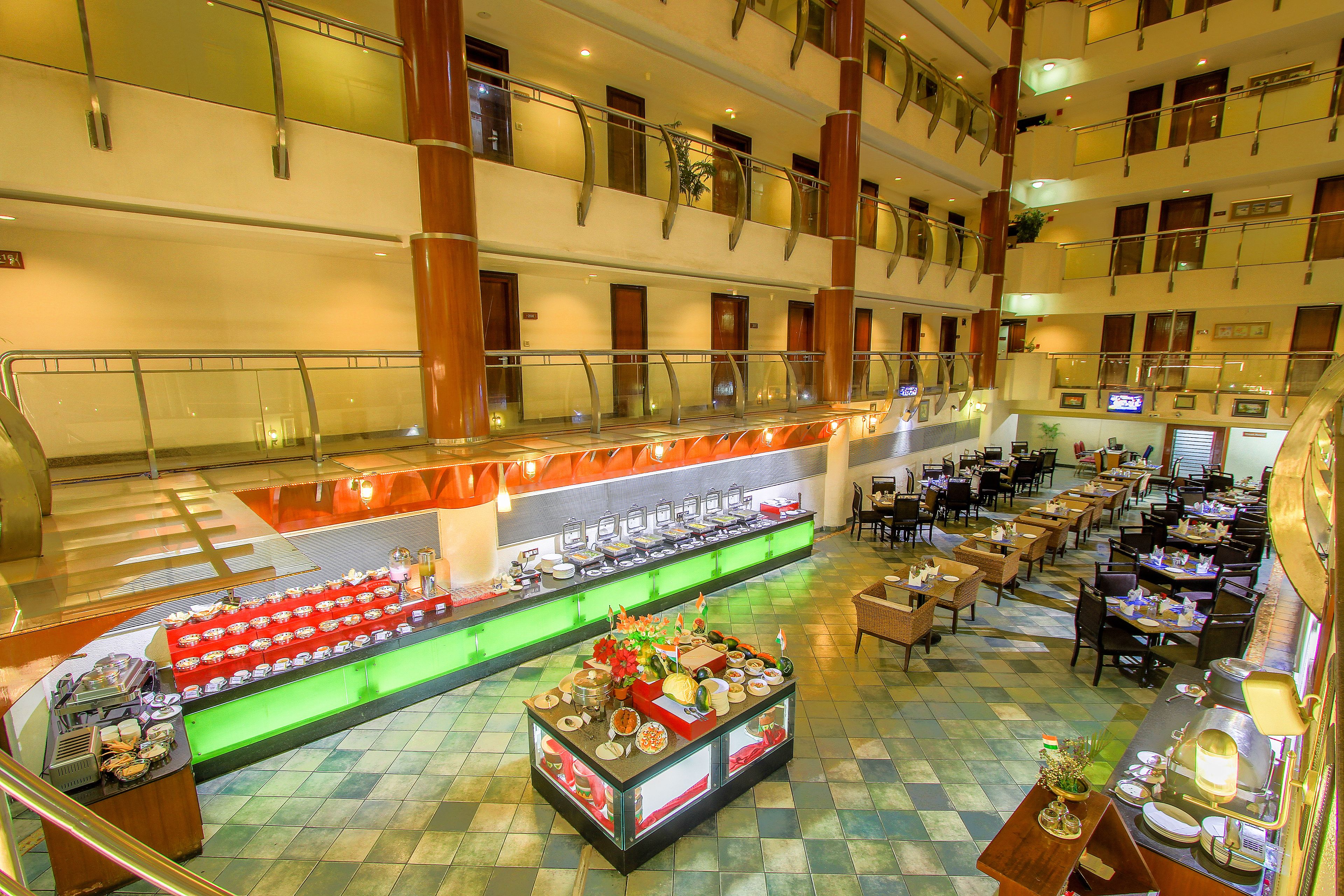 A multi-level hotel lobby with a buffet area, seating arrangements, and a staircase.