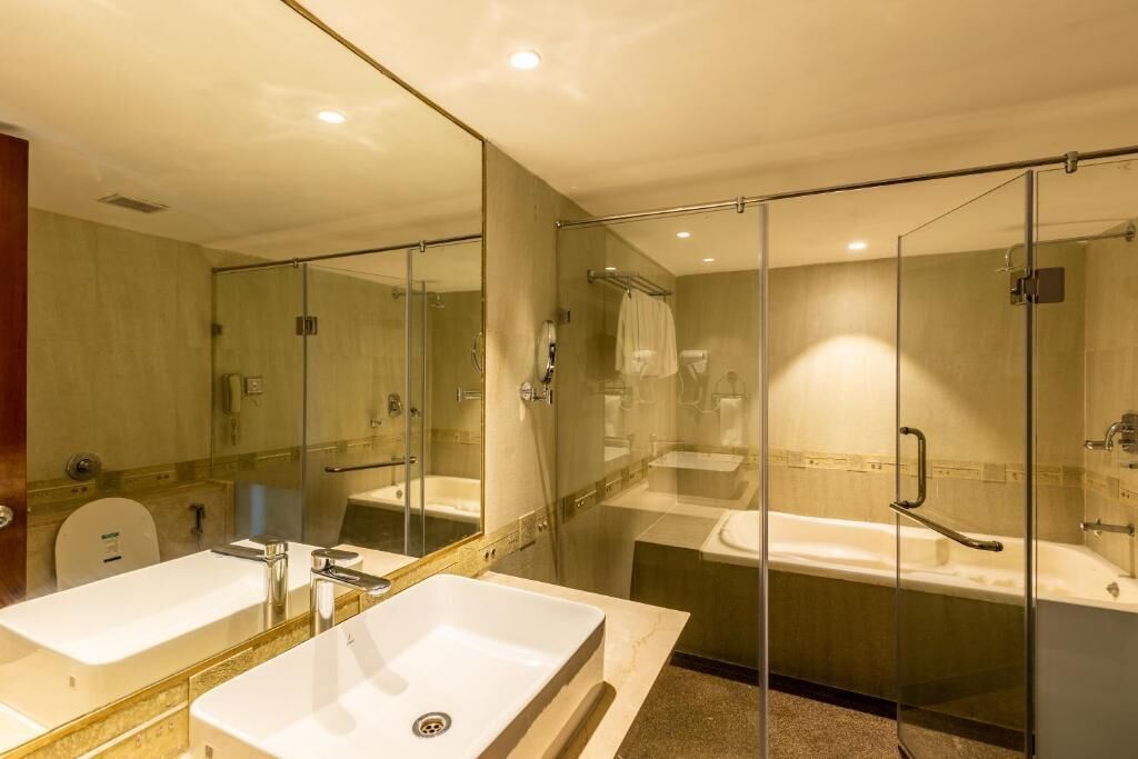 A modern bathroom with a large mirror, two sinks, a bathtub, and a glass shower enclosure.