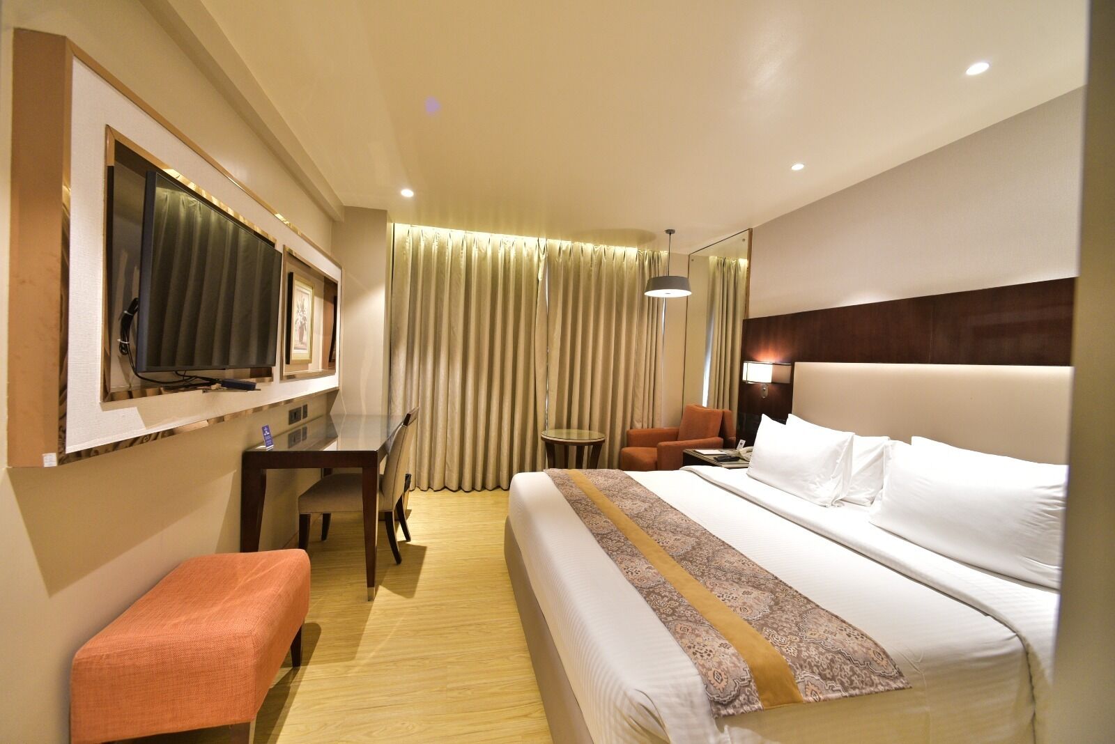Una habitación de hotel con cama, escritorio, silla, televisión y una mesita.