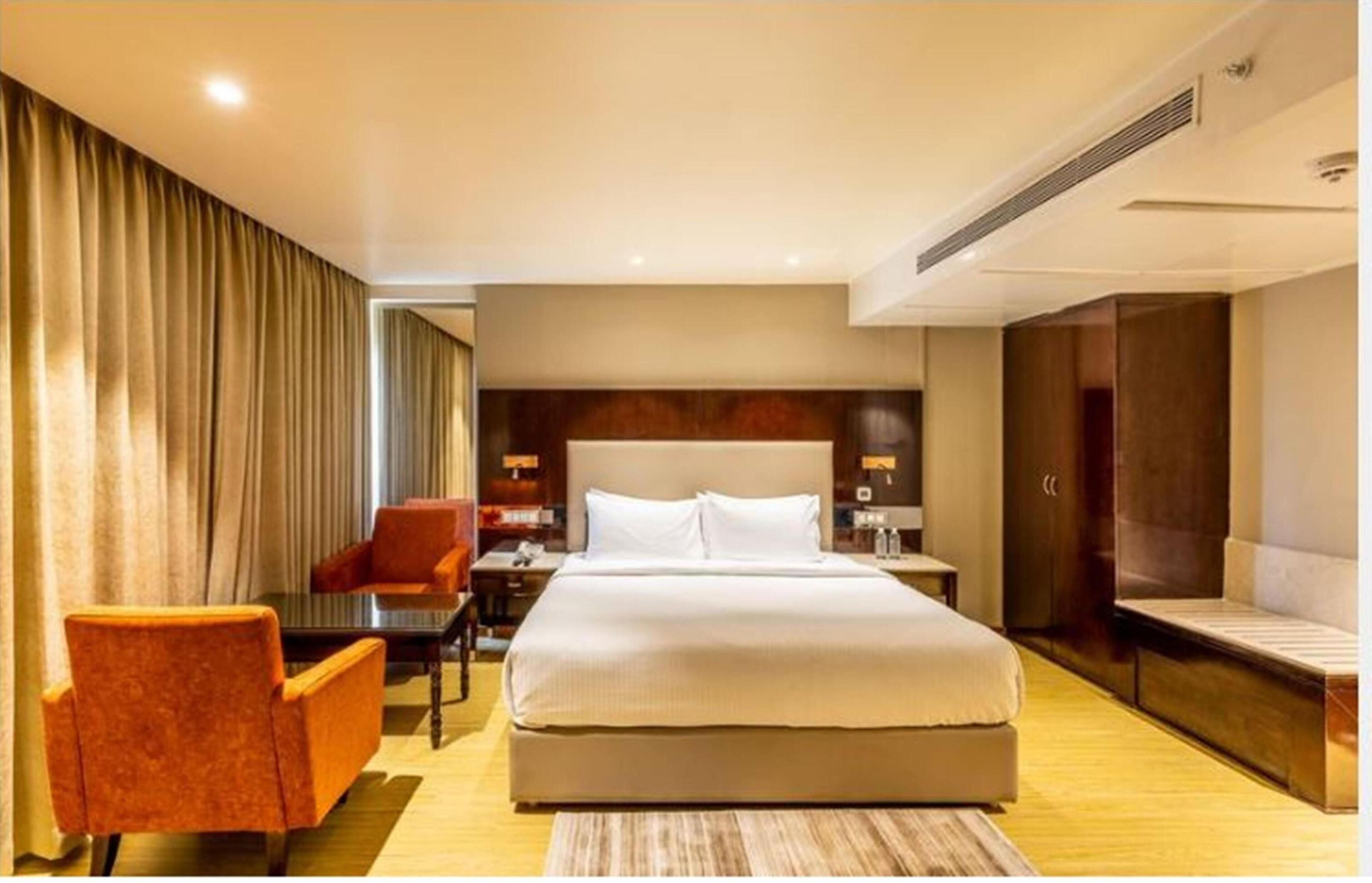 Una habitación de hotel con una cama grande, un escritorio con silla, un sofá y un armario.