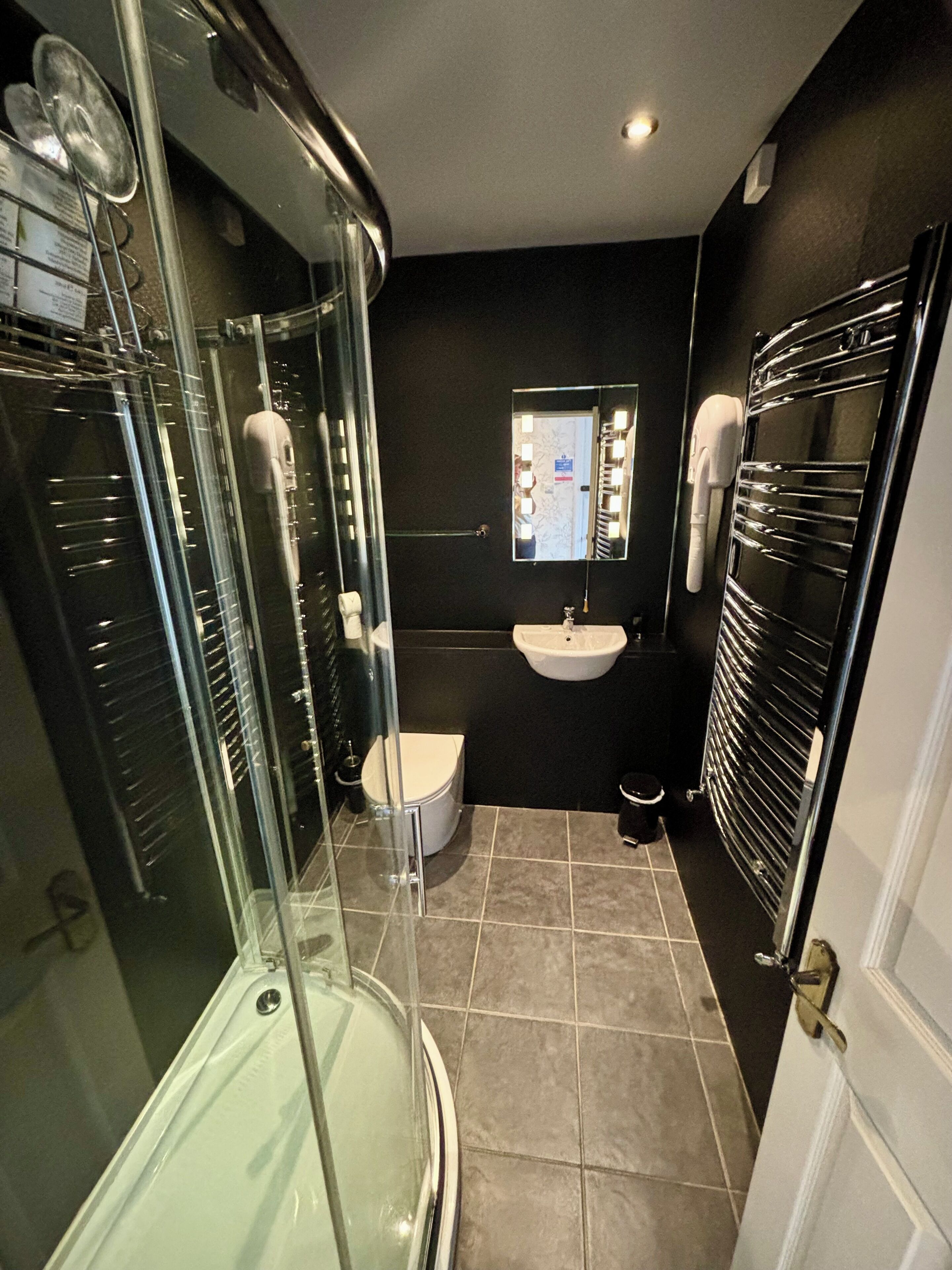 Une salle de bain moderne avec une douche à parois de verre, un lavabo blanc et un miroir avec éclairage intégré.