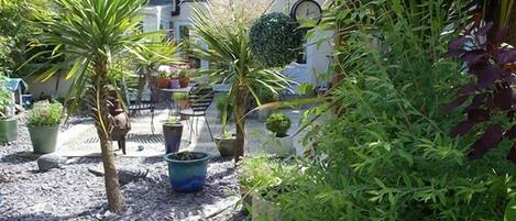 Een binnentuin met plantenpotten, een tafeltje en stoelen.